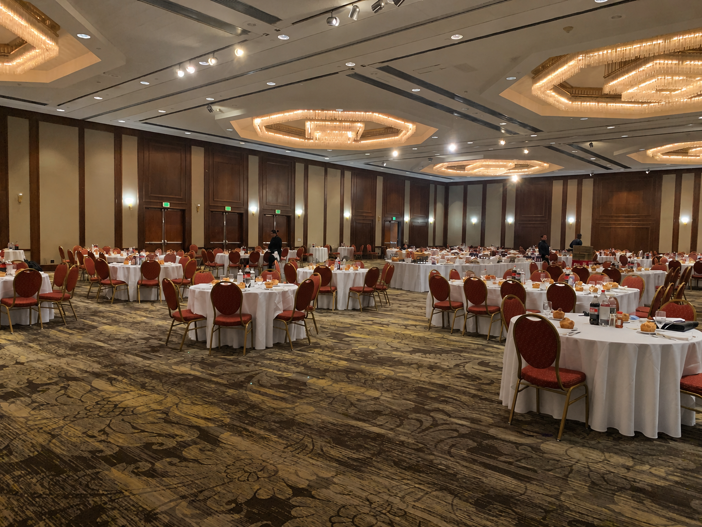 Large ballroom arranged with round tables and long white linens