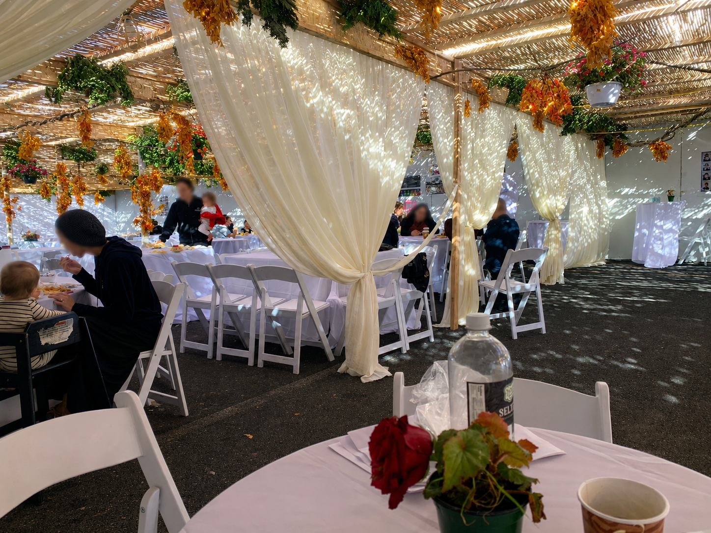 Covered kosher dining area with white draping and greenery