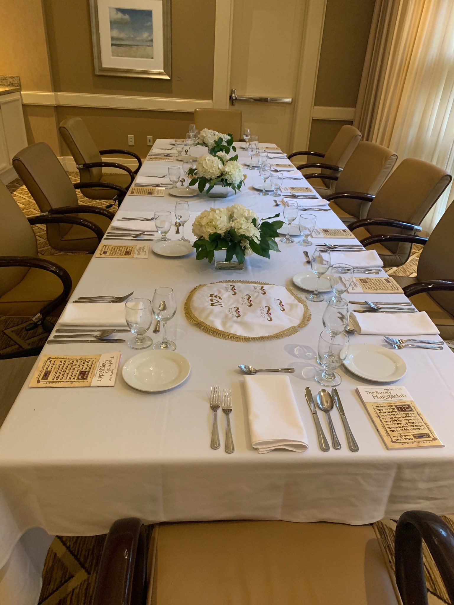 Formal Jewish dining table with Haggadah materials and white flowers